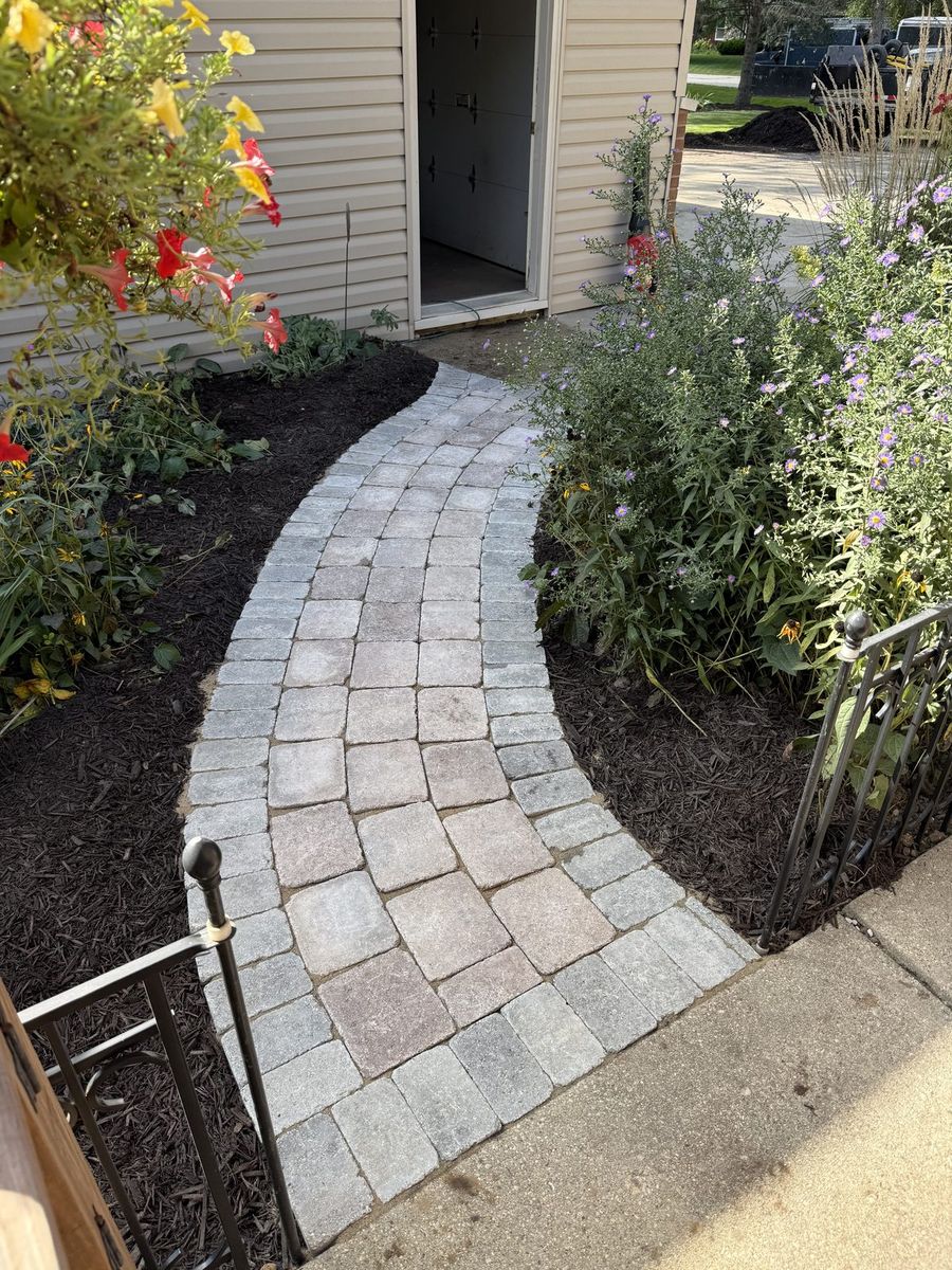Finished paver walkway with fresh mulch beds near the house, after